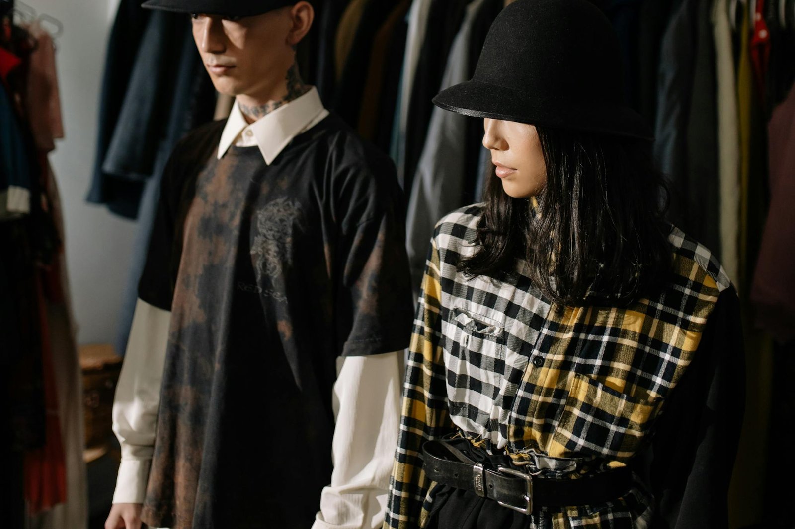 Fashion-forward man and woman wearing stylish hats and plaid shirts in a clothing store.