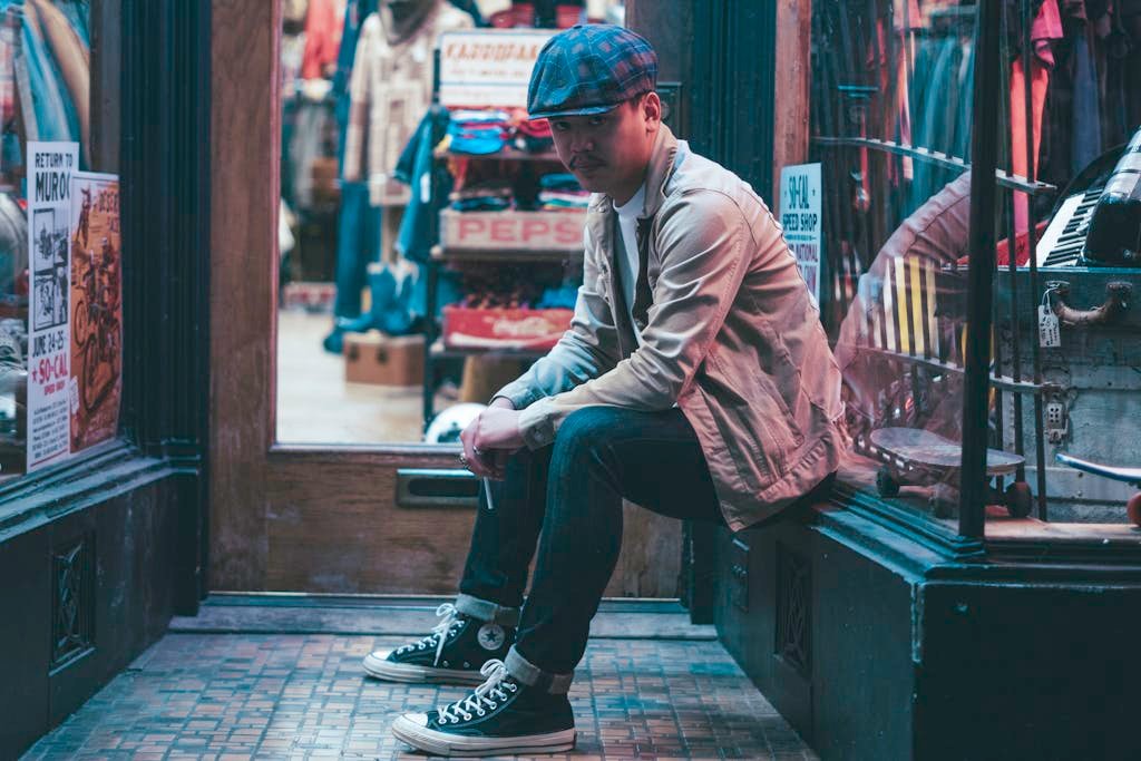 Stylishly dressed person sitting in a vintage urban store setting, exuding modern fashion vibes.