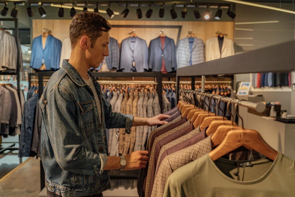 Young man browsing suits in a stylish clothing store, exploring fashion options.